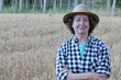 Portrait of mature female farmer smiling on farmland while crossing her arms 