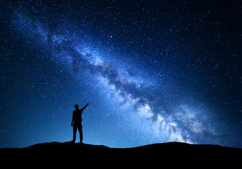 Wall Mural - milky way. silhouette of a standing man pointing finger in night starry sky on the mountain. colorfu