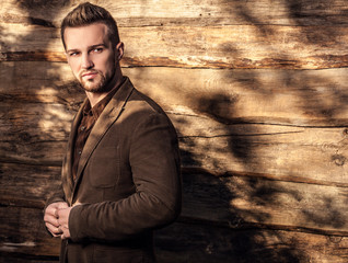 Portrait of young beautiful fashionable man against wooden wall.