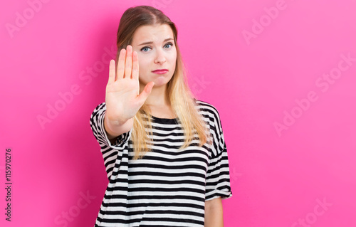 Fotografie, Obraz Young woman making a stop pose on a pink background