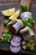 Herring rollmops with red and green onion, gherkins and lemon