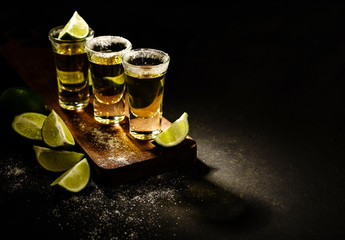 Mexican Gold Tequila with lime and salt on wooden table, selective focus. Copyspace.