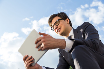 Canvas Print - Smiling businessman using tablet outside