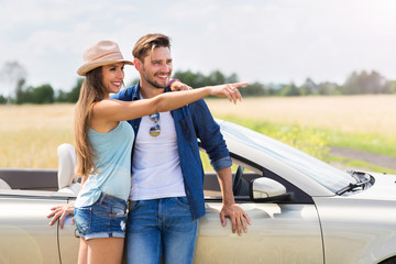 Wall Mural - Young couple standing near convertible
