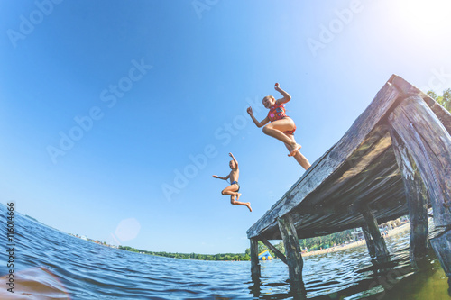 Fototapety skoki do wody  dzieci-chlopiec-i-dziewczynka-skacza-z-drewnianego-molo-w-wodzie-tonowanie