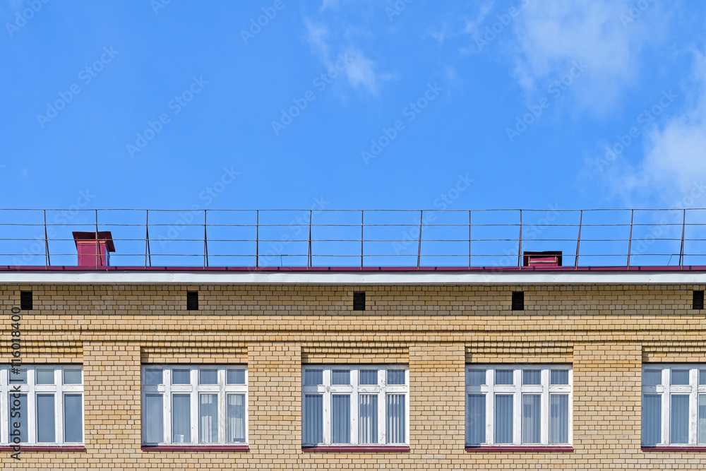 Brick facade of the house with a roof and white windows against the ...