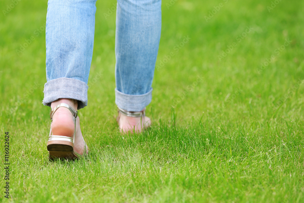 Female feet in sandals on green grass
