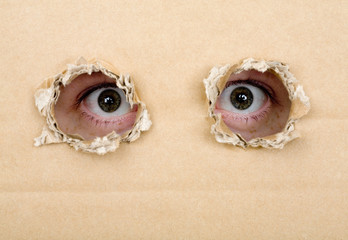 Eye looking from a holes in a cardboard