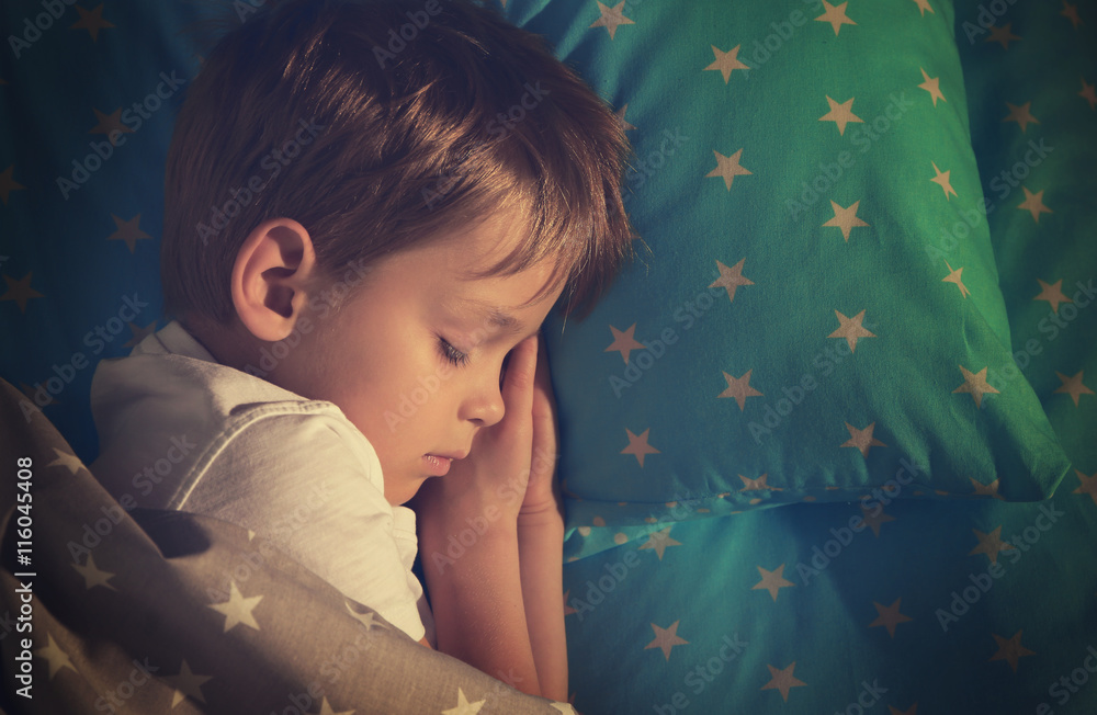 Adorable little boy sleeping in bed
