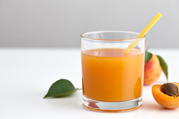 Glass of fresh apricot juice with yellow straw