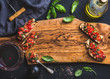 Tomato and basil bruschetta with glass of red wine, olive oil, salt, fresh herbs on wooden board over black background, copy space
