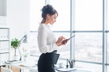 Wall Mural - Close-up side view portrait of an employee texting, sending and reading messages during her break at the workplace.