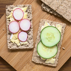 Wall Mural - Wholemeal rye crispbread with brie cheese, radish and cucumber slices, photographed overhead with natural light