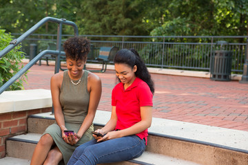 Wall Mural - 2 young african american college students looking at their cell phones