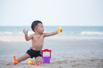 Little Asian boy 1 year old playing sand on the beach