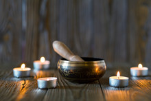 Singing Bowl On Dark Wooden Background. Burning Candles And Oil For Aromatherapy And Massage..