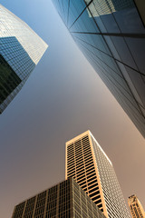 Bottom view of modern skyscrapers in business district in evening light at sunset with lens flare filter effect