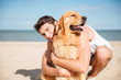 © Drobot Dean - Cheerful young man hugging his dog on the beach