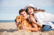 Couple with dog laughing and having fun on the beach