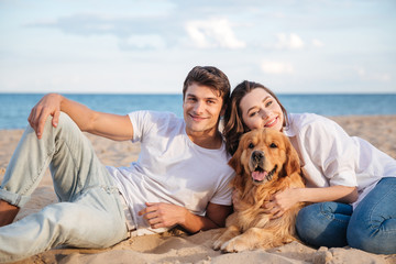 Poster - Couple with their dog lying and relaxing on the beach