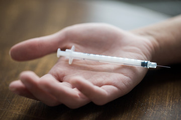 close up of addict hand and used drug syringe