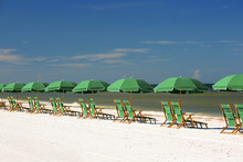 Row Of Green Umbrellas With Beach Chairs Facing The Waters Edge

