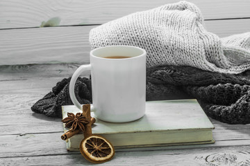 Wall Mural - Cup of tea on a beautiful wooden background with winter sweater, old book