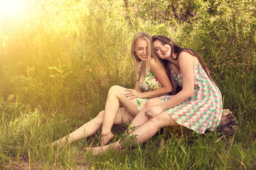 Two happy friends siting on grass and smile