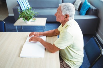 Wall Mural - senior man using braille to read