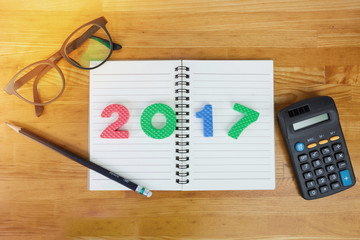 Happy new year 2017 number on notepad with glasses, pencil and c