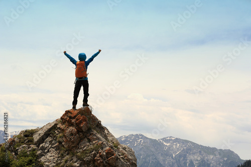 Cuadros en Lienzo cheering successful woman backpacker open arms on mountain peak
