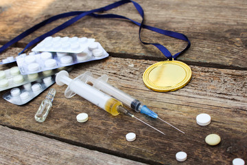 Sports medal and medicines on a wooden background. Toned image. 