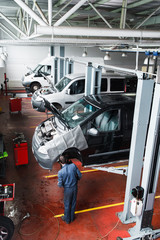 Car repair shop usual working day, auto service interior. Top view on garage with cars on maintenance and mechanic working with automobiles