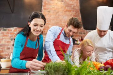 Wall Mural - happy friends and male chef cooking in kitchen