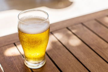 Glass of light beer on the wooden table.