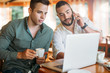 © minastefanovic - Two man at cafe using laptop and mobile phone