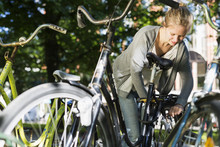 Young Woman Locking Bicycle At Parking Lot