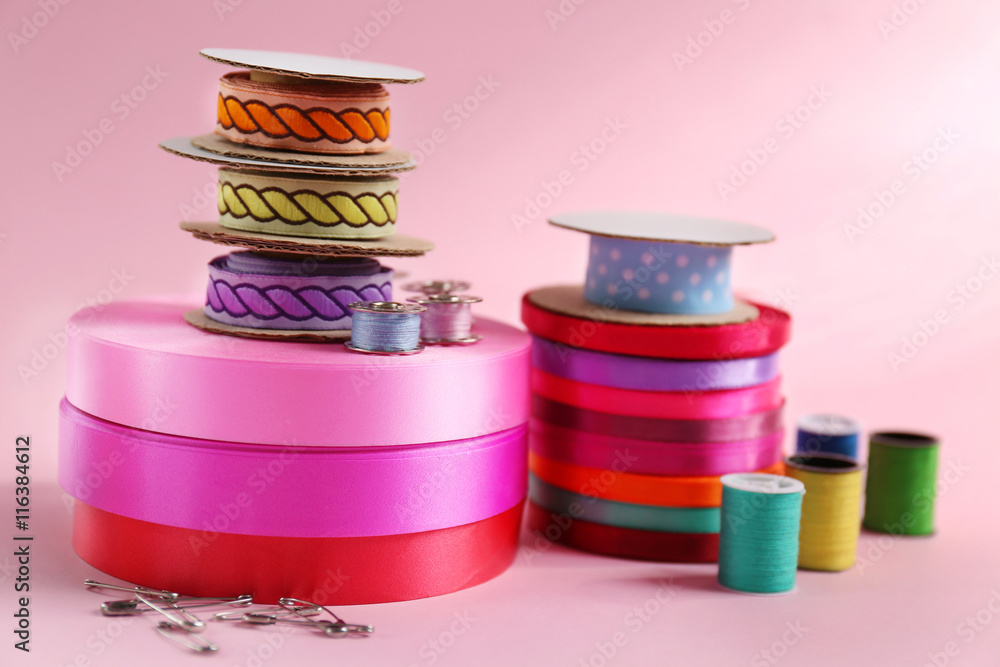 Many ribbons and sewing accessories on color background