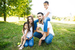 © mintybear - Parents Sitting With Children In Field Of Summer Flowers.Happy family having weekend in summer park