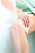 Kobieta pielęgnuje nogi pod prysznicem, wcierając balsam w chusteczkach