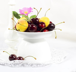 Ripe sweet cherry and apricots in a white vase for fruit     selective focus    design, effects, toning
