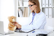 © rogerphoto - Female doctor examining a .Teddy bear  patient by stethoscope. Children medical care concept