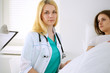 © rogerphoto - Young beautiful female doctor sitting near the bed of her patient in hospital.