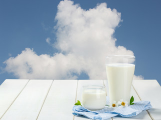 Two glass of milk with Napery on a white wooden table on a blue