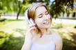 © mintybear - Teenage girl with headphones  outdoors on sunny summer day smiling. Beautiful millennial young woman listening to music relaxing. Horizontal, retouched,