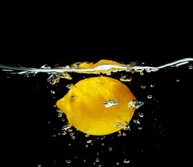 Sticker - Fresh juicy lemon falling in water on dark background