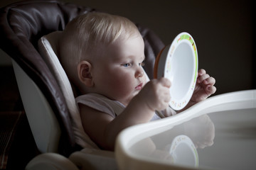 Baby boy sitting at a table for feeding with an empty plate