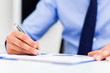 © Minerva Studio - Businessman sitting at office desk signing a contract
