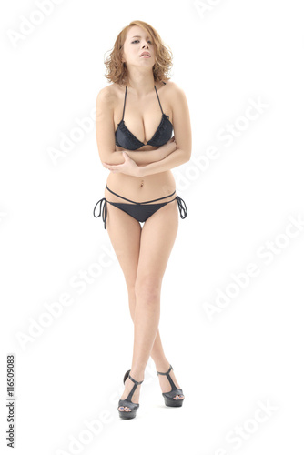 金髪の女性モデルが 黒いビキニの水着を着て立っています この画像はスタジオで撮影されて物で 背景は白バックです Stock Foto Adobe Stock