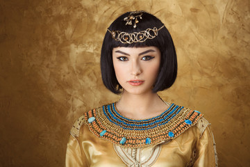 Beautiful woman like Egyptian Queen Cleopatra on golden background